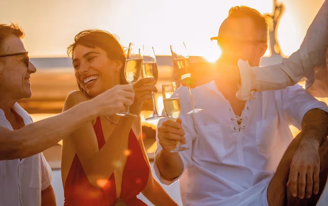 Happy guests toasting champagne on a Lagos sunset boat tour with glowing golden hour backdrop