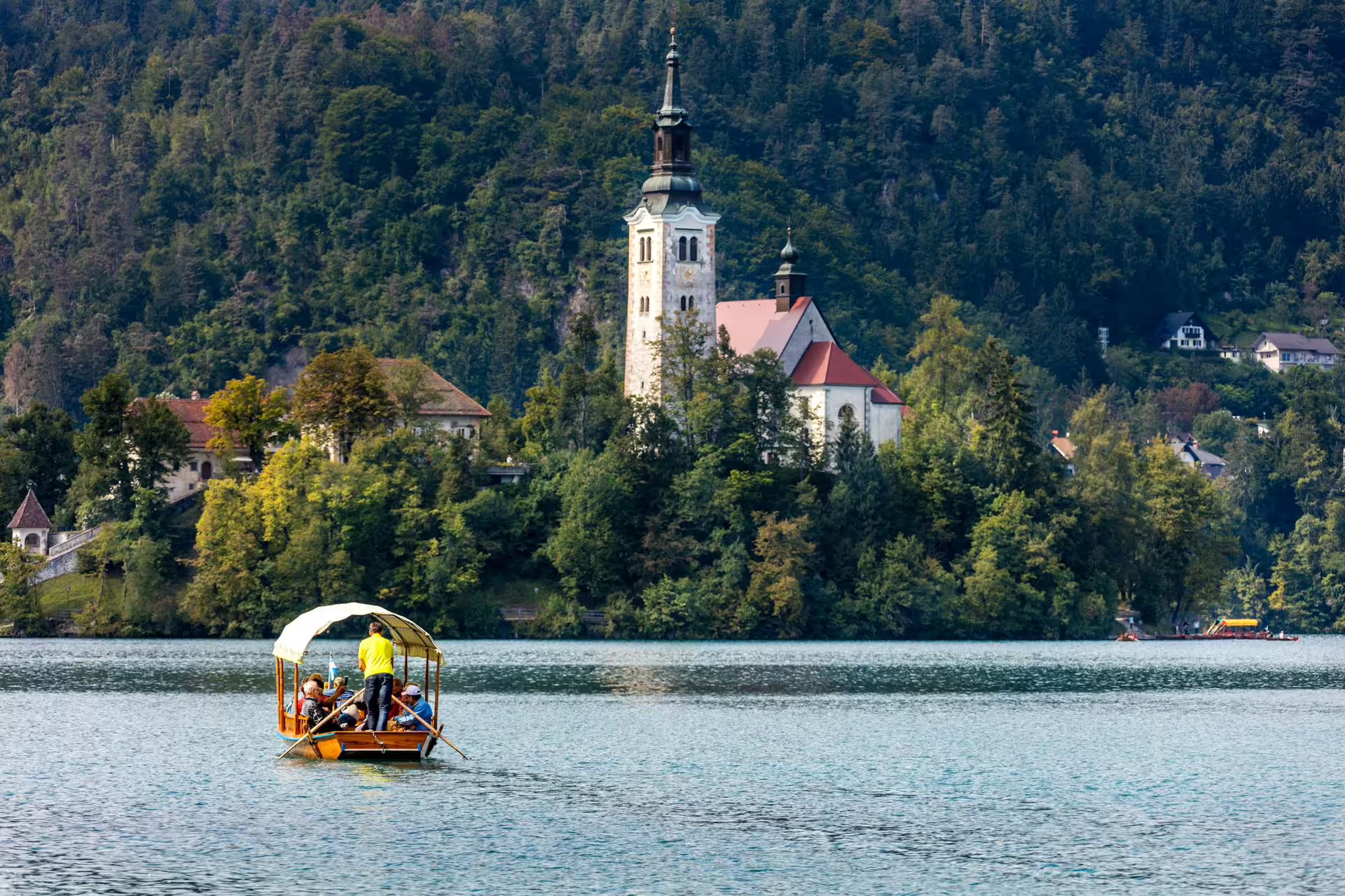 Traditional pletna boat ride on Lake Bled in summer with Bled Island Church backdrop, Slovenia tour