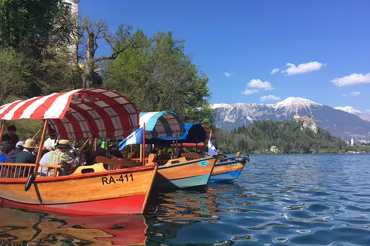 Pletna boats on Lake Bled with Alps backdrop, summer boat ride experience paired with Bled Castle visit