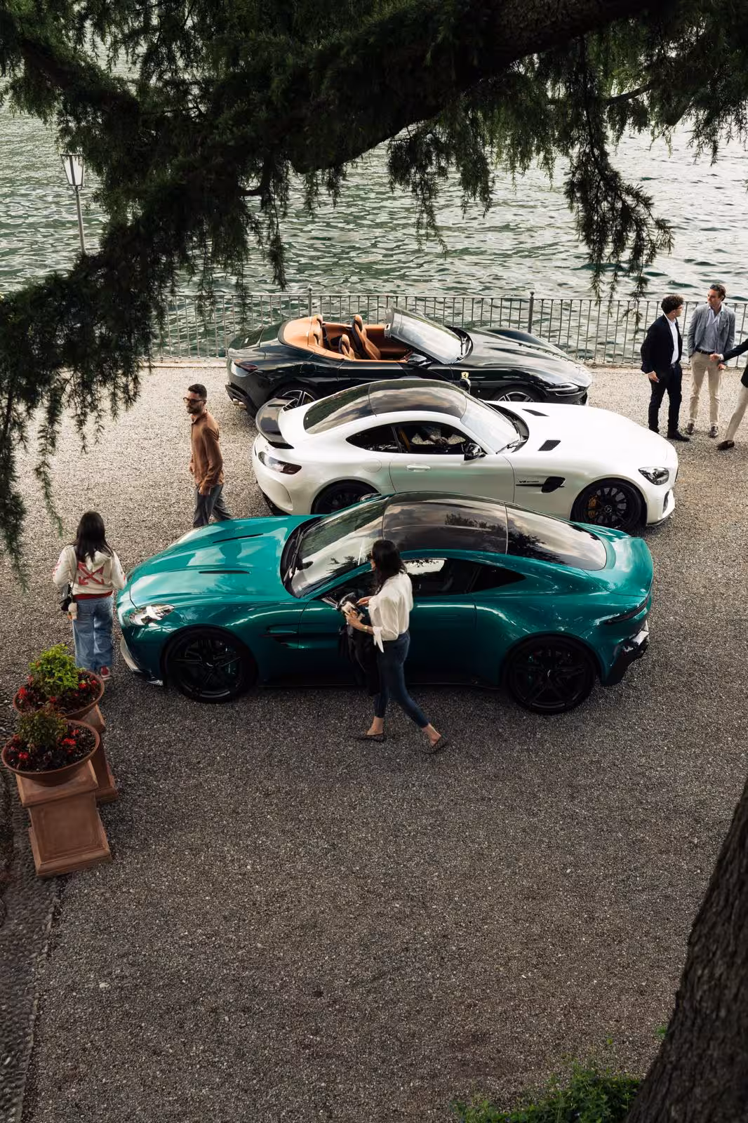 Guests exploring luxury supercars including Aston Martin Vantage and Mercedes AMG GT at an exclusive Lake Como supercar tour event