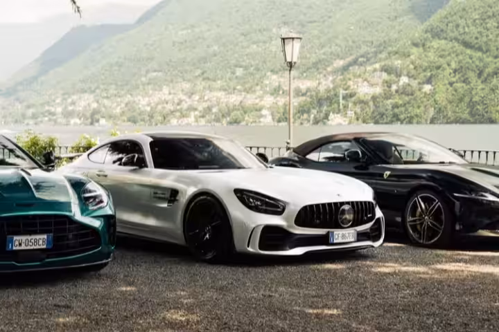 Mercedes-AMG GT supercar flanked by Aston Martin and Ferrari at Lake Como scenic overlook
