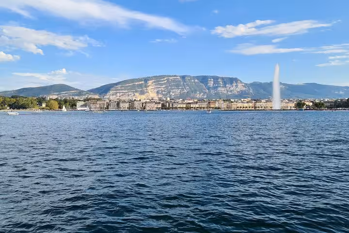 Scenic view of Lake Geneva with Jet d'Eau fountain and cityscape backdrop on a sunny day.