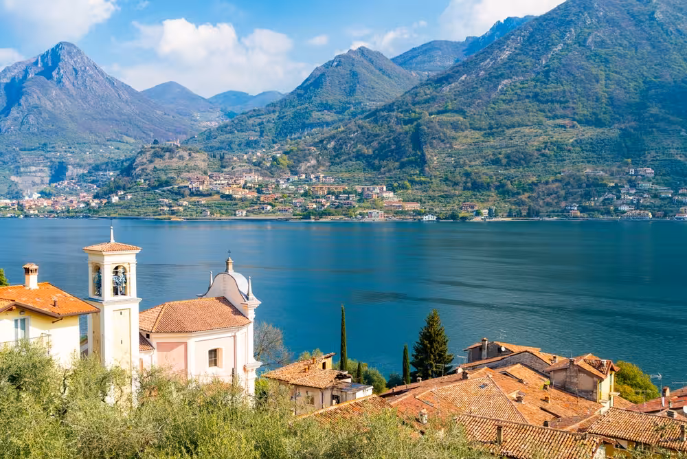 Scenic view of Lake Iseo with charming Italian village and majestic mountains, ideal for a relaxing cruise adventure.
