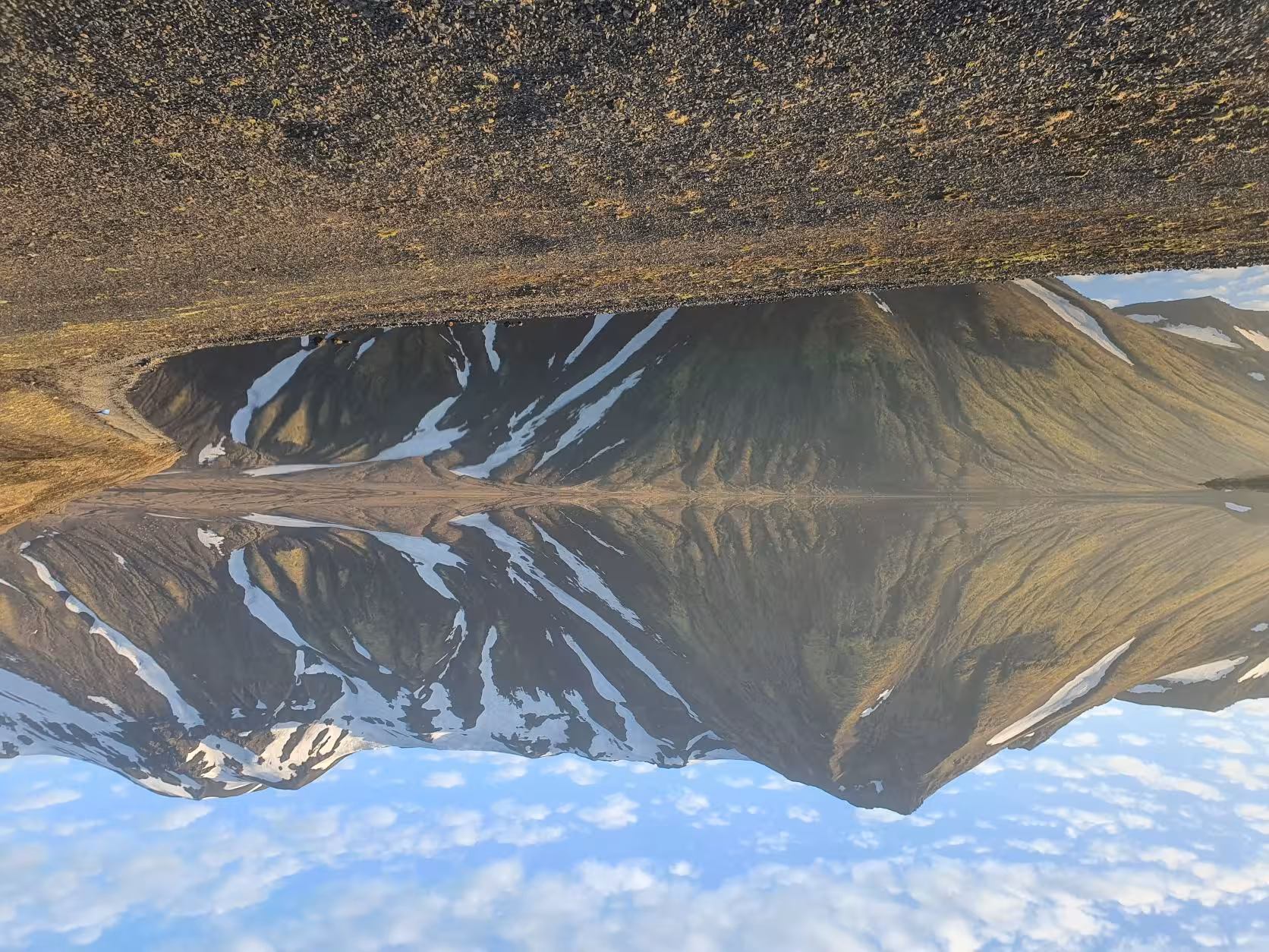 Snow-streaked volcanic mountains reflected in the still waters of Lake Langisjor, Iceland Highlands