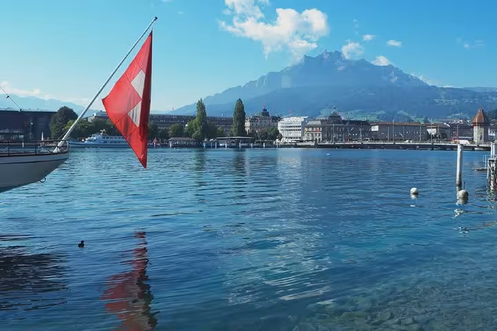 Swiss flag on boat with Lake Lucerne waterfront and Mount Pilatus in background