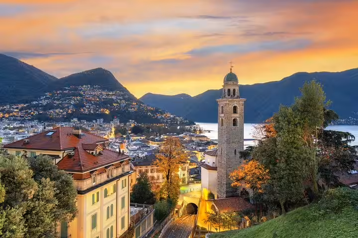 Sunset over Lake Lugano and historic bell tower, scenic highlight on Milan to Switzerland private day tour