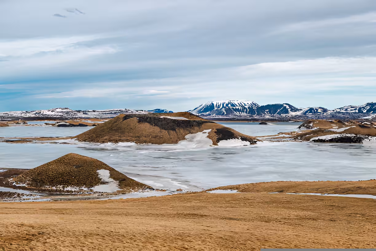 Frozen Lake Myvatn with volcanic pseudocraters and snow-dusted mountains in Iceland winter landscape