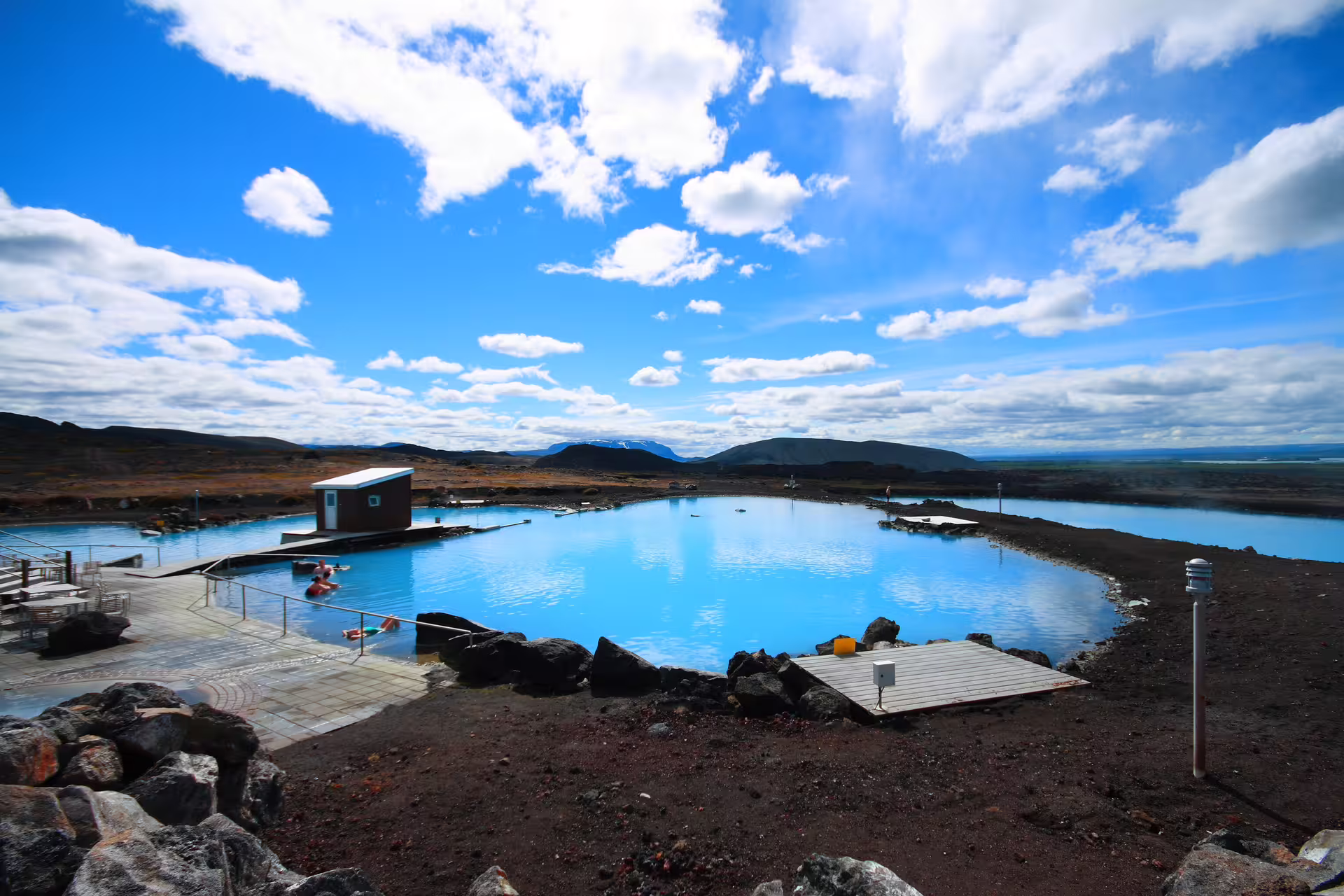 Vivid blue geothermal waters of Lake Myvatn Nature Baths with volcanic landscape and mountains in Iceland