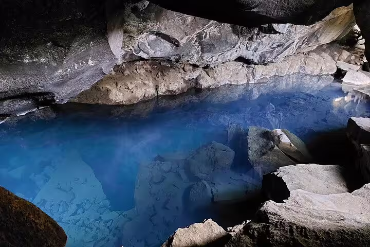 Steaming blue geothermal cave pool with rocky walls at Lake Myvatn, Iceland