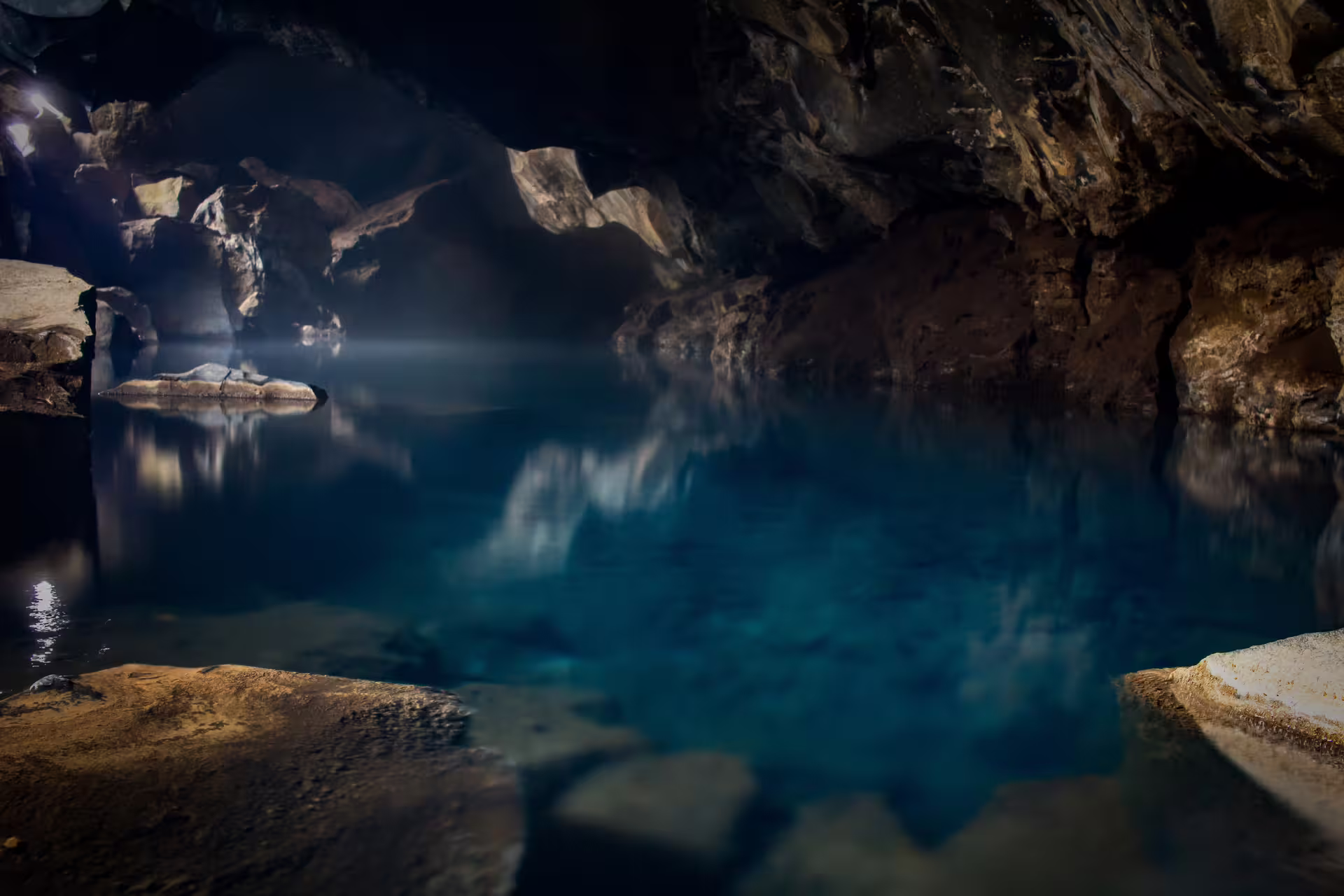Geothermal cave pool with glowing blue water and rocky walls at Lake Myvatn Iceland
