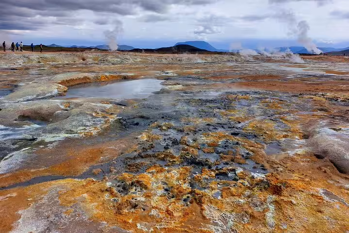 Colorful geothermal hot springs and sulfur deposits at Lake Myvatn, Iceland, with steam vents and mountains in background
