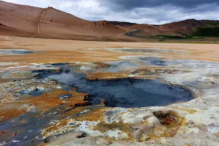 Steaming boiling mud pools with colorful mineral deposits at Lake Myvatn geothermal area, Iceland