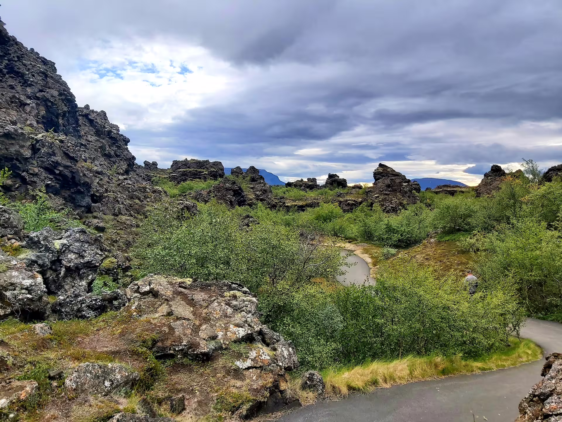 Volcanic lava rock formations and green shrubs at Lake Myvatn, Iceland, with dramatic cloudy sky