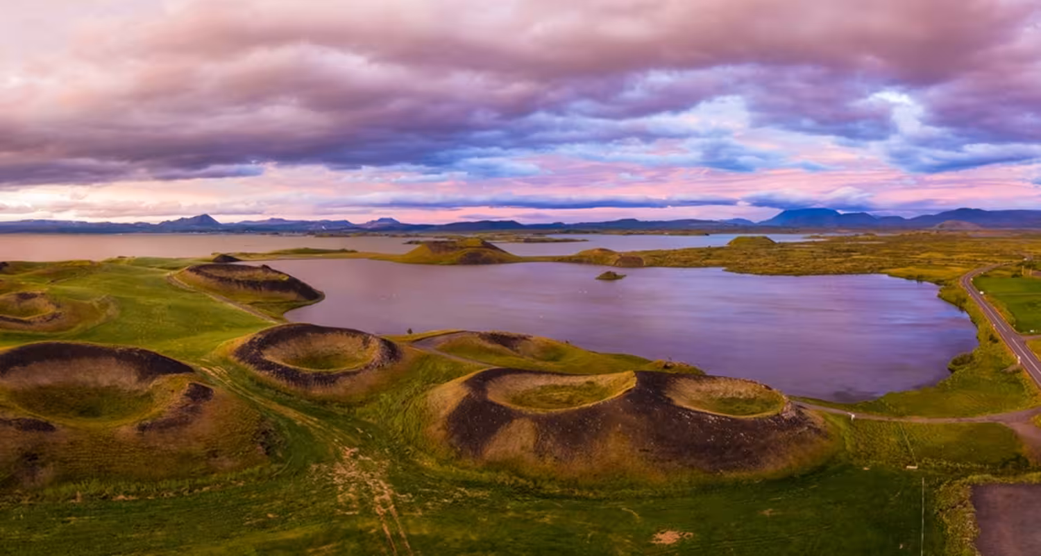 Aerial view of Lake Myvatn pseudocraters and volcanic landscape under a pink and purple sunset sky, Iceland