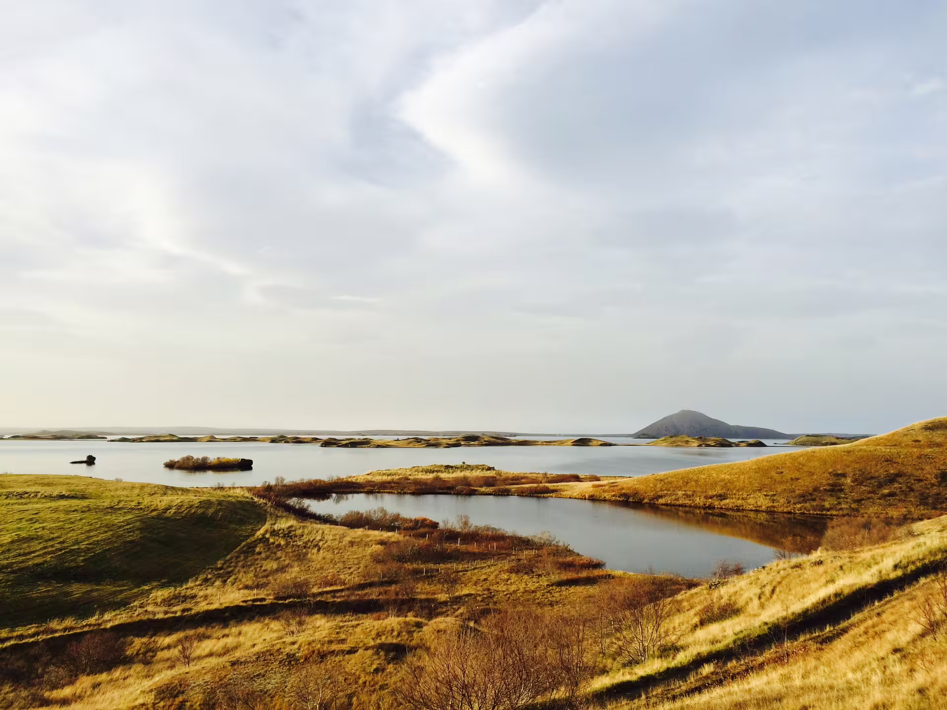 Panoramic view of Lake Myvatn with volcanic pseudo-craters, small islands, and a cinder cone in Iceland