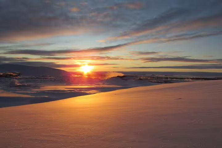 Golden sunset over snow-covered landscape near Lake Myvatn, Iceland, with glowing reflections on the snow