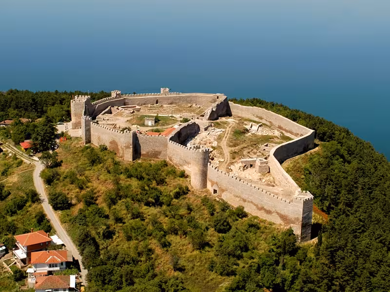 Aerial view of the historic stone fortress overlooking Lake Ohrid, surrounded by greenery and panoramic vistas.