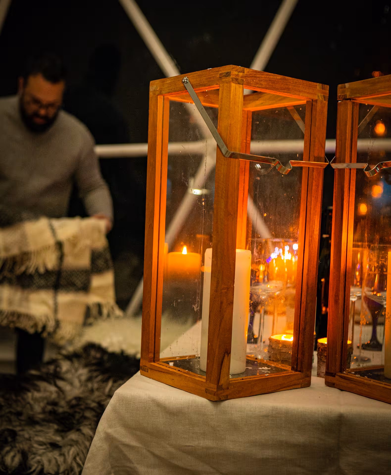 Warm wooden lanterns with glowing candles create an intimate ambiance for a wine tasting and food pairing experience by the lake