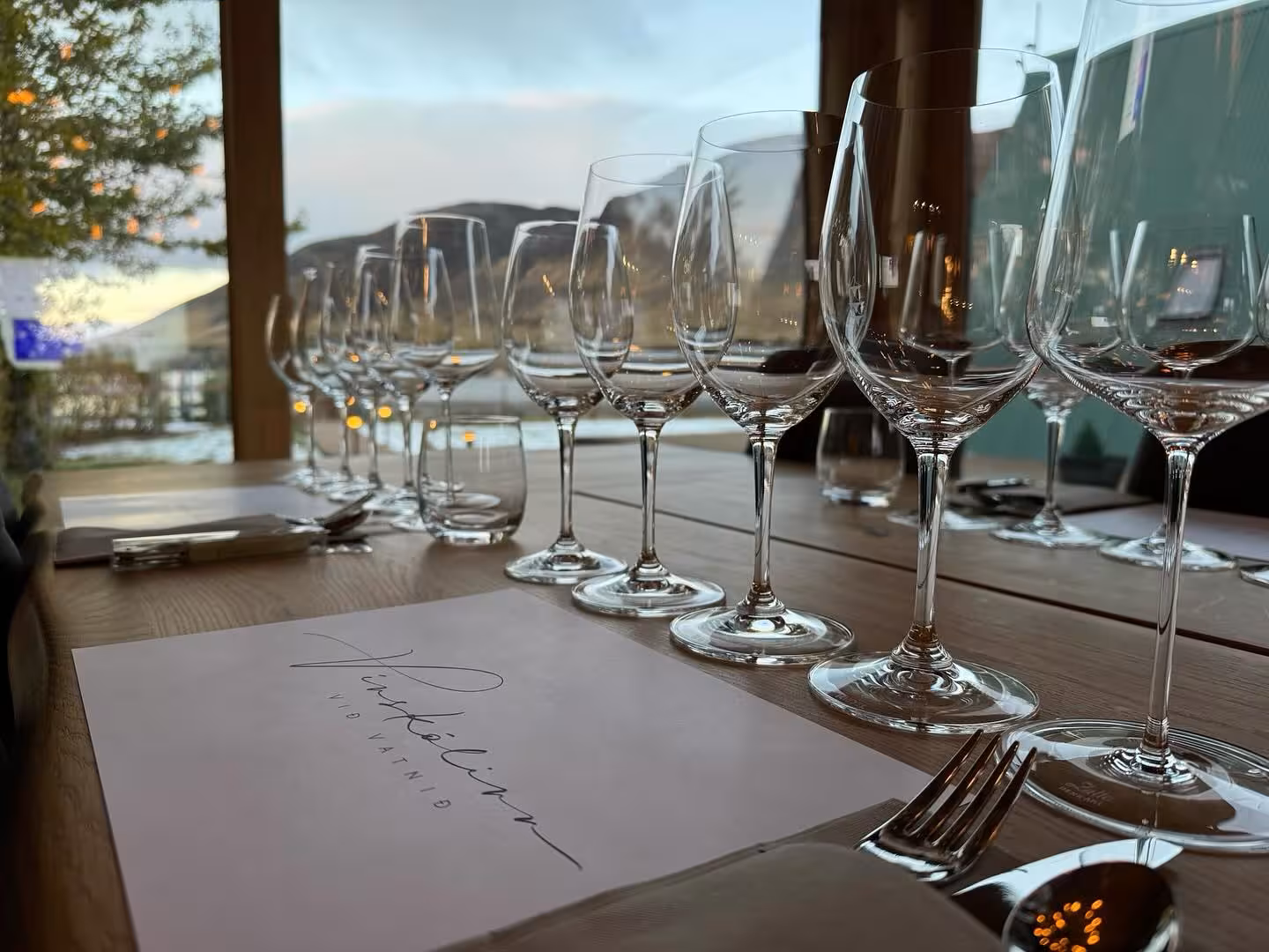 Elegant wine glasses lined up on a lakeside restaurant table set for a scenic wine tasting experience