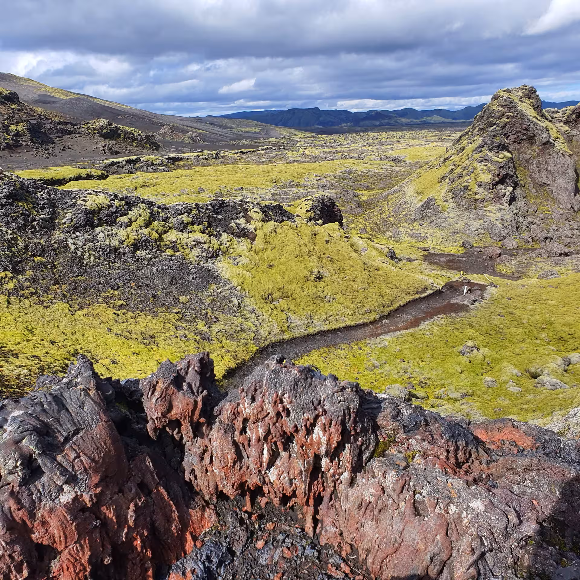 Laki lava field covered in bright green moss with red volcanic rocks in South Iceland