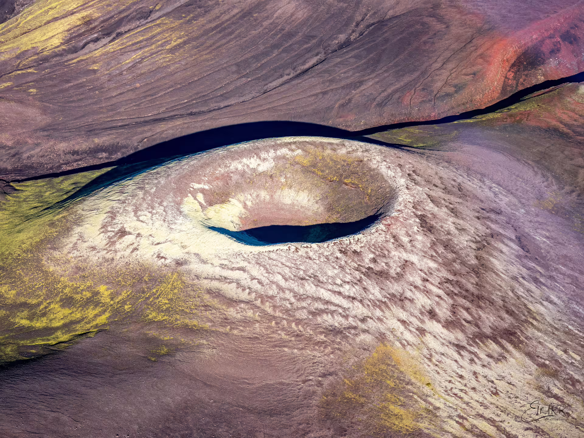 Aerial view of a volcanic crater cone surrounded by a dark lake at Laki Craters, Iceland