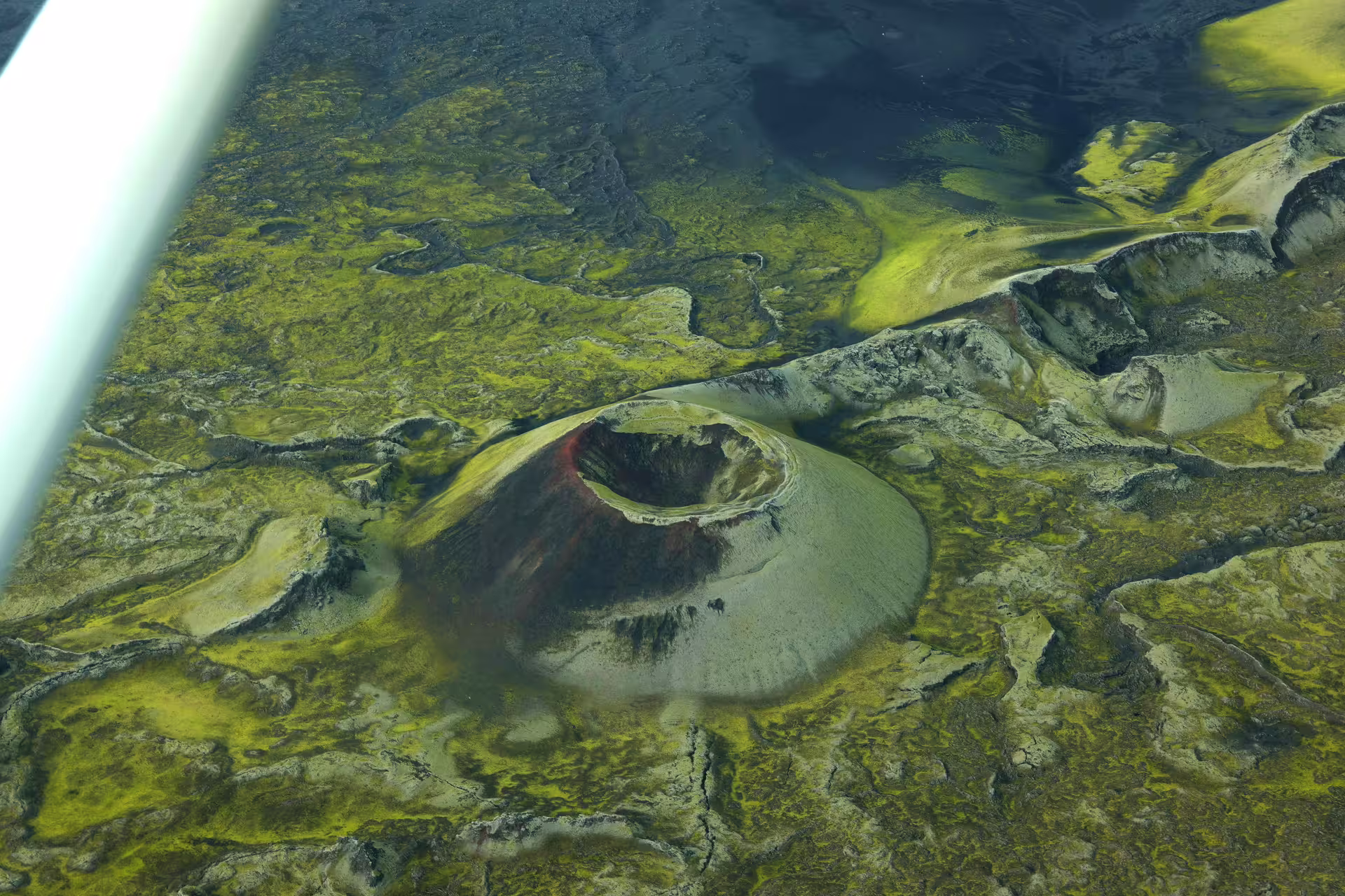 Aerial view of a volcanic crater cone surrounded by green moss-covered lava fields in Iceland