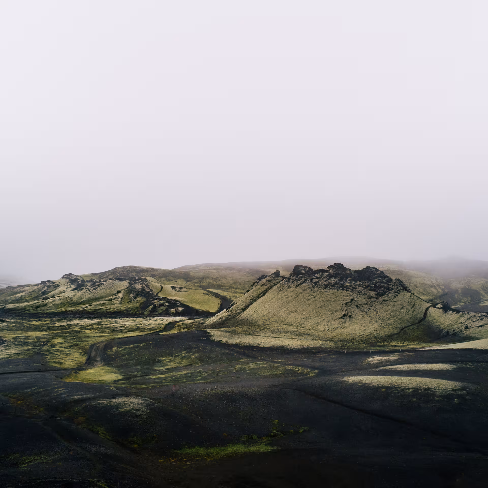Misty volcanic highland landscape with black lava fields and green craters explored on a private Laki super jeep tour from Vik Iceland