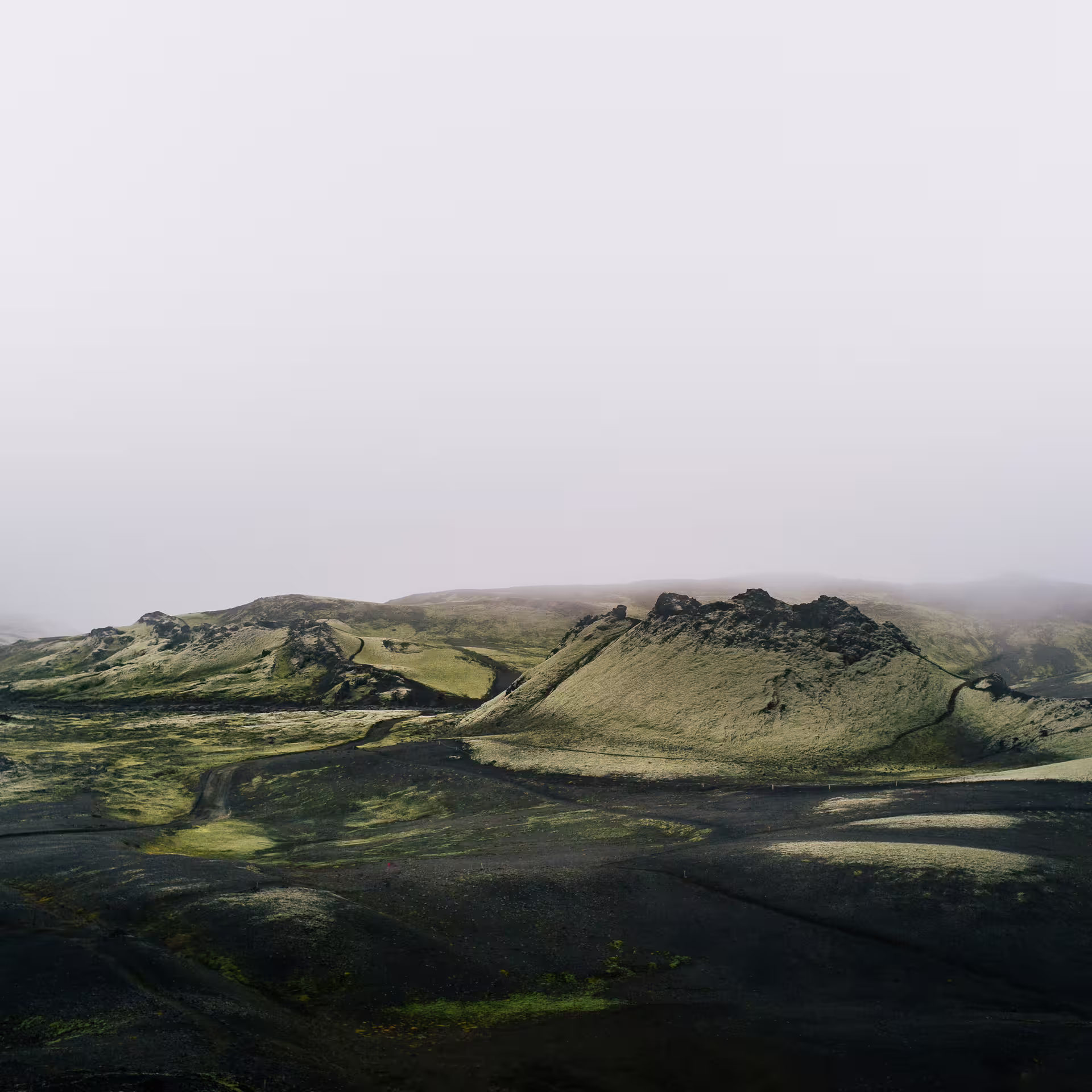 Misty volcanic landscape with green moss and black lava fields at Laki Craters on a private super jeep tour from Vik Iceland
