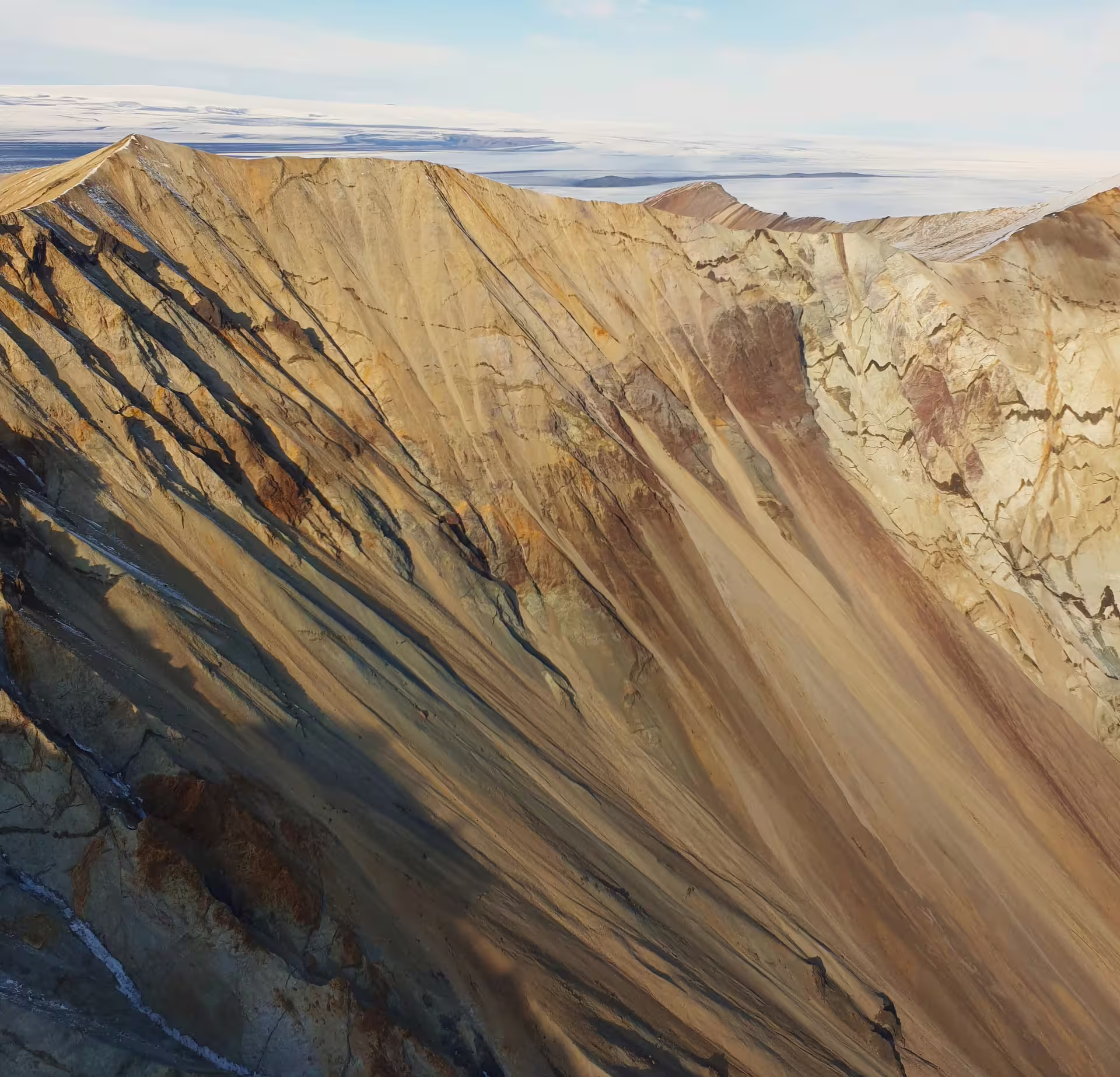 Aerial view of colorful striated volcanic rock ridges at Laki Craters, Iceland, with snow-covered plains in background