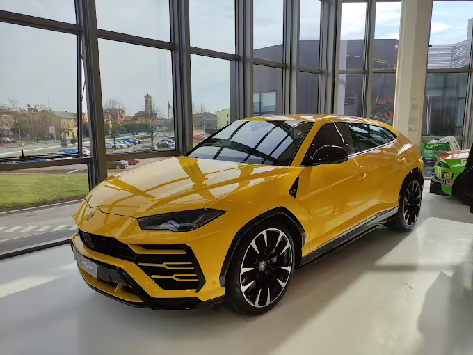 Admire the stunning yellow Lamborghini Urus displayed in the sunlight-filled showroom at the Lamborghini Museum.