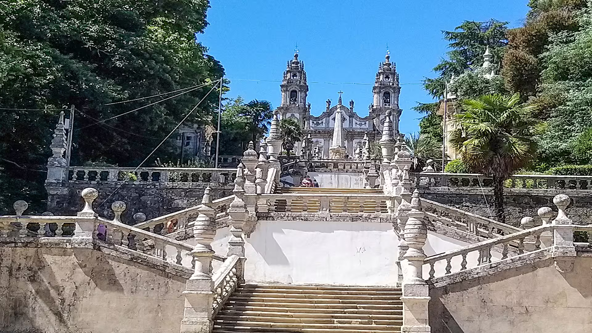 Majestic staircase leading to the Sanctuary of Our Lady of Remedies in Lamego, Portugal, surrounded by lush greenery.