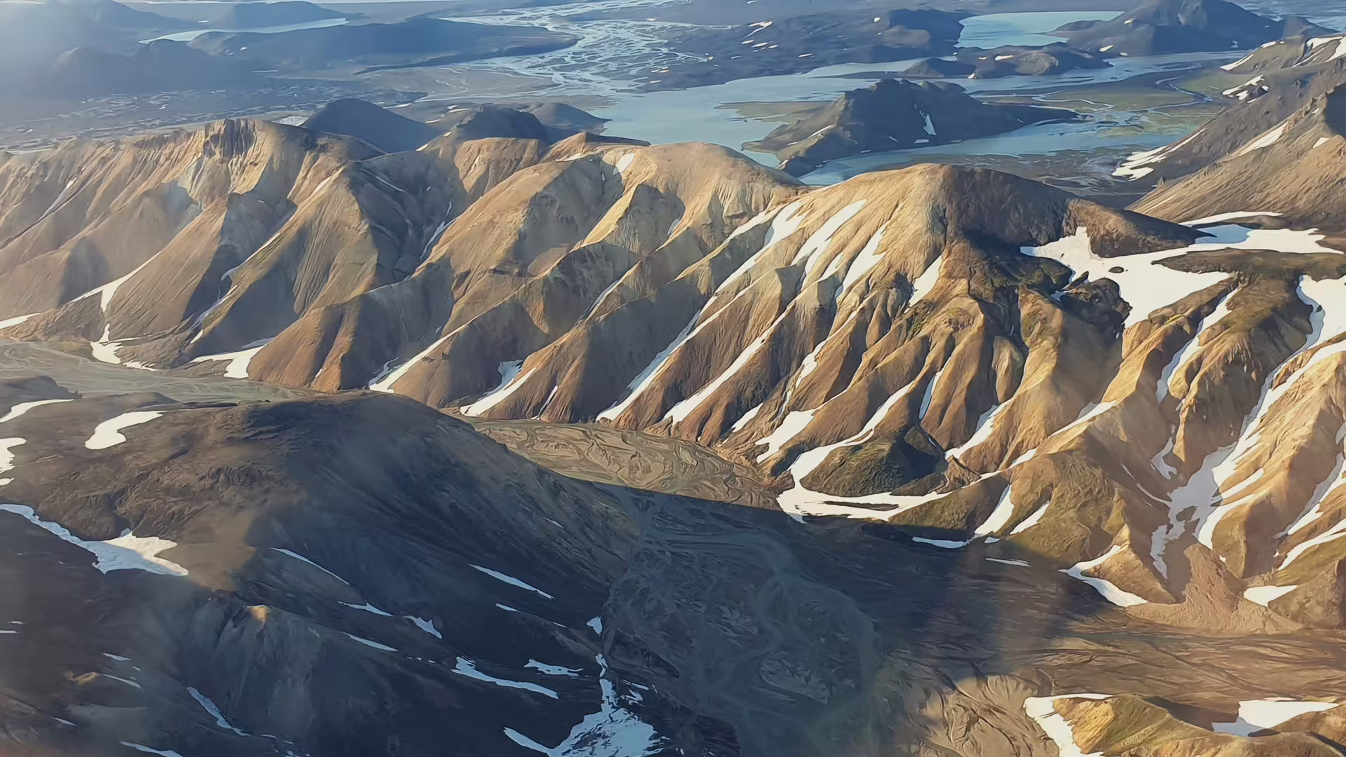 Aerial view of Landmannalaugar colorful rhyolite mountains with snow patches and lakes in Iceland