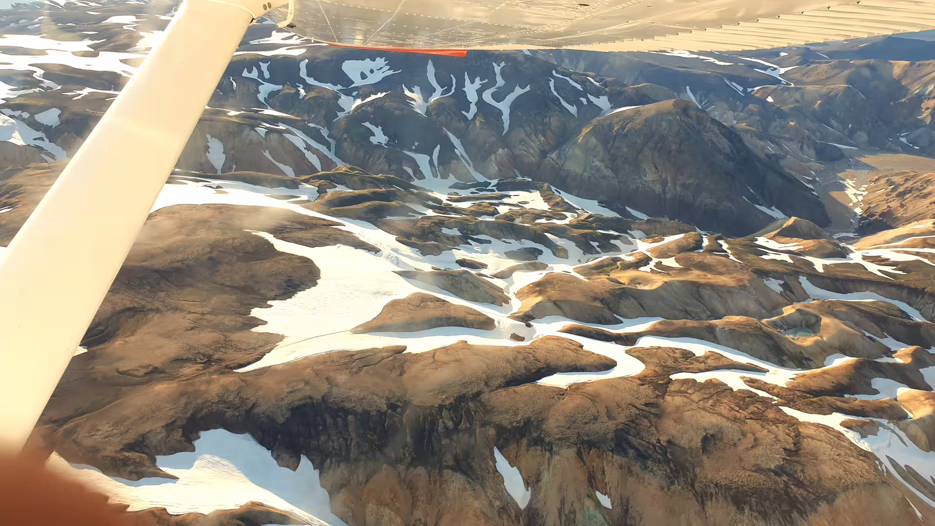 Aerial view of snow-patched Landmannalaugar mountains in Iceland seen from small airplane window