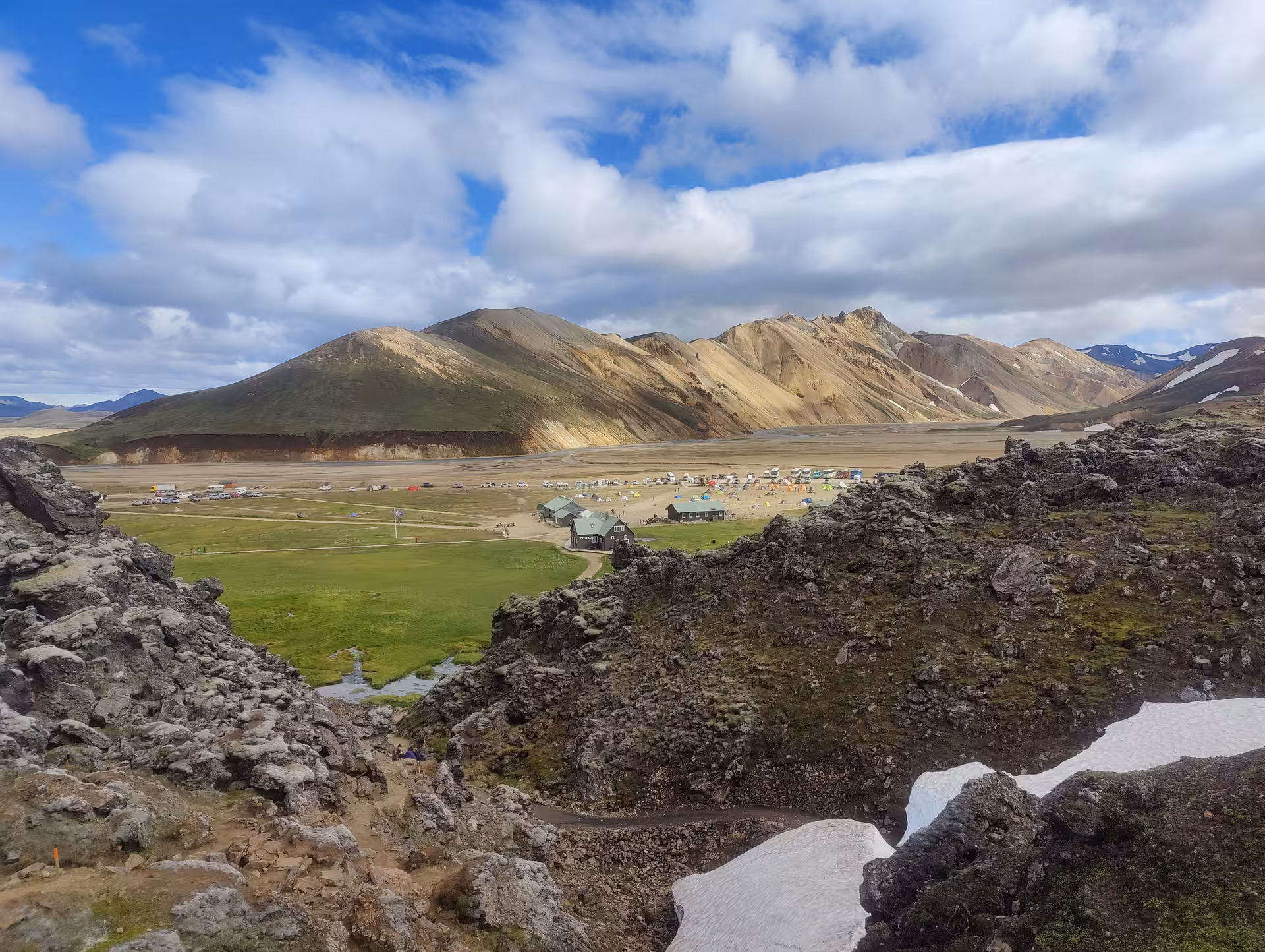 Aerial view of Landmannalaugar campsite and hut surrounded by colorful rhyolite mountains and lava fields, Iceland
