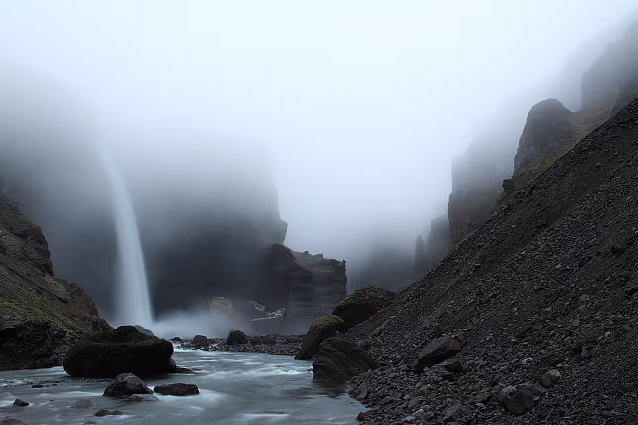 Misty canyon waterfall flowing into rocky river at Landmannalaugar rhyolite highlands Iceland
