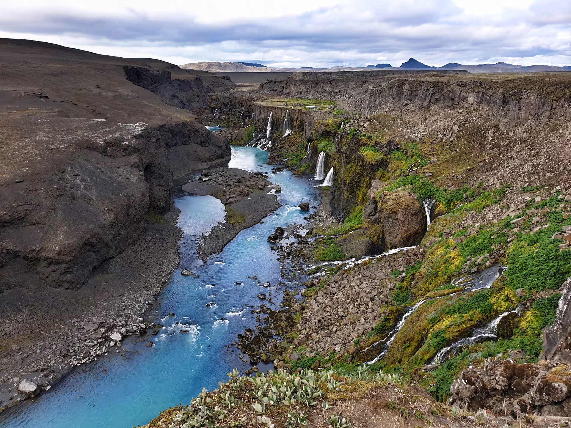 Turquoise glacial river winding through Sigöldugljúfur canyon with cascading waterfalls, Landmannalaugar highlands Iceland