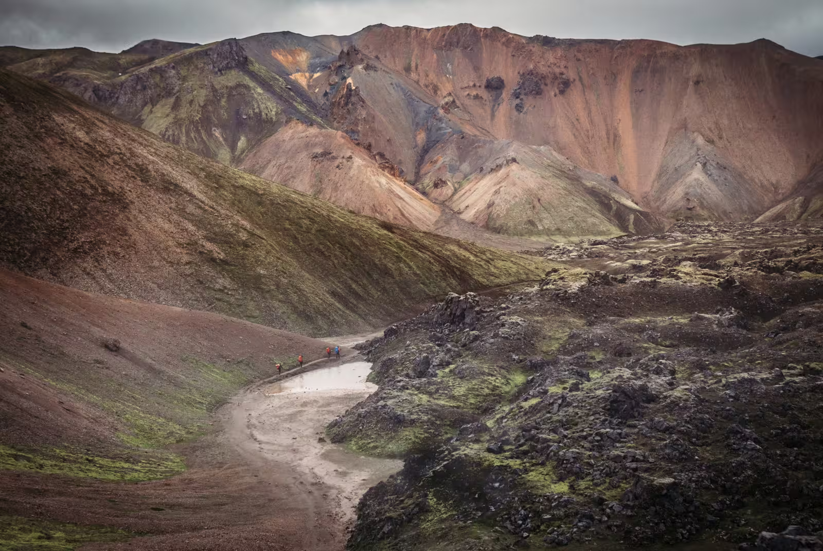Hikers crossing a river in Landmannalaugar's colorful volcanic highland landscape, Iceland