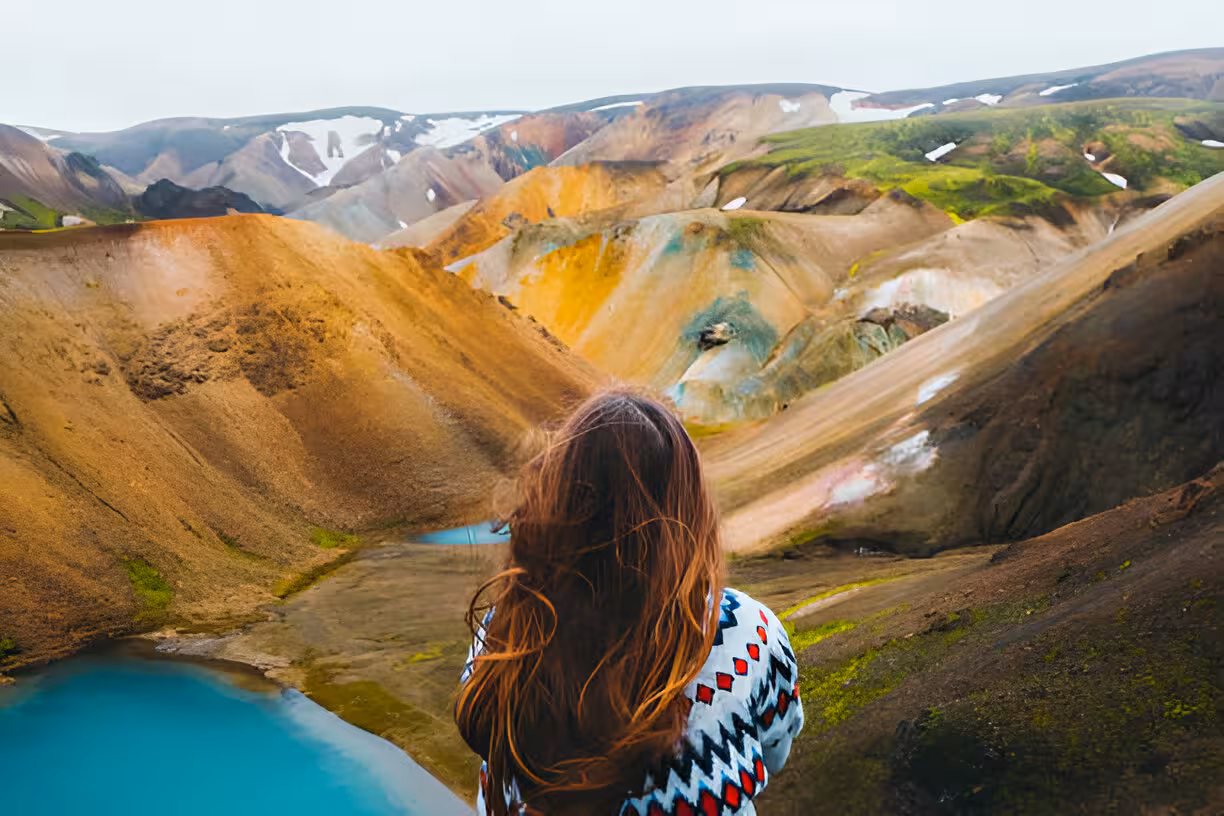 Woman overlooking colorful rhyolite mountains and turquoise geothermal pools at Landmannalaugar Iceland