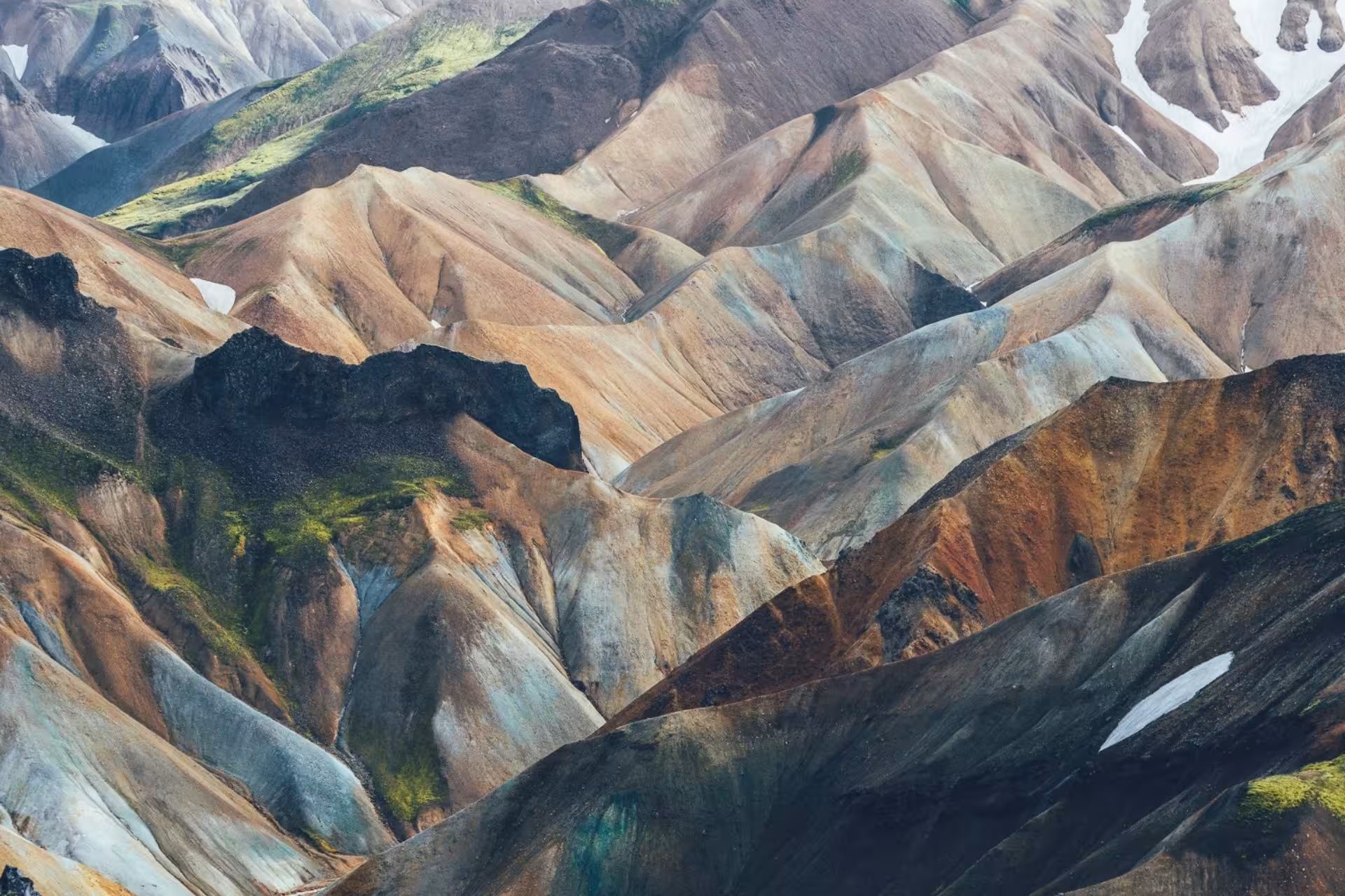 Colorful rhyolite mountains of Landmannalaugar highlands with patches of snow and green moss