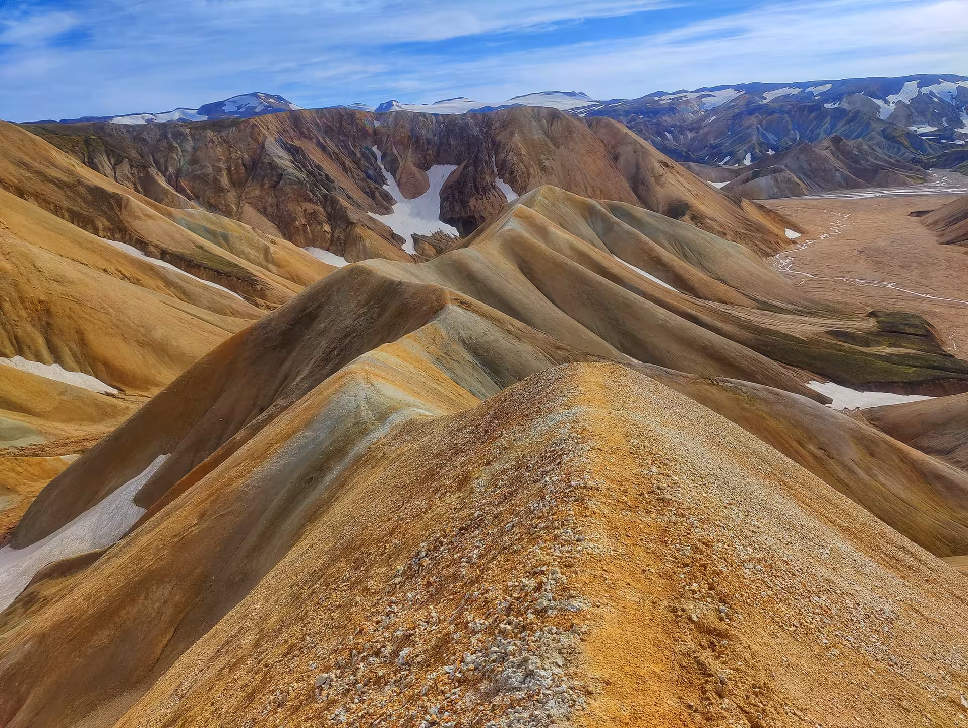 Colorful rhyolite mountains of Landmannalaugar with snow patches under blue sky, Iceland