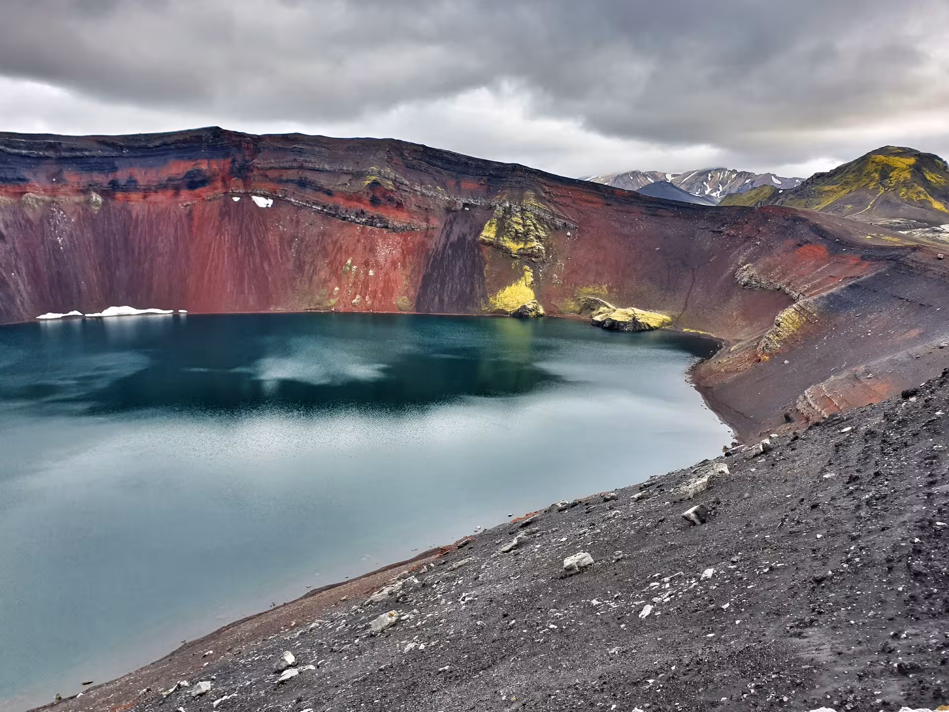 Turquoise crater lake with vivid red volcanic walls at Landmannalaugar, Iceland