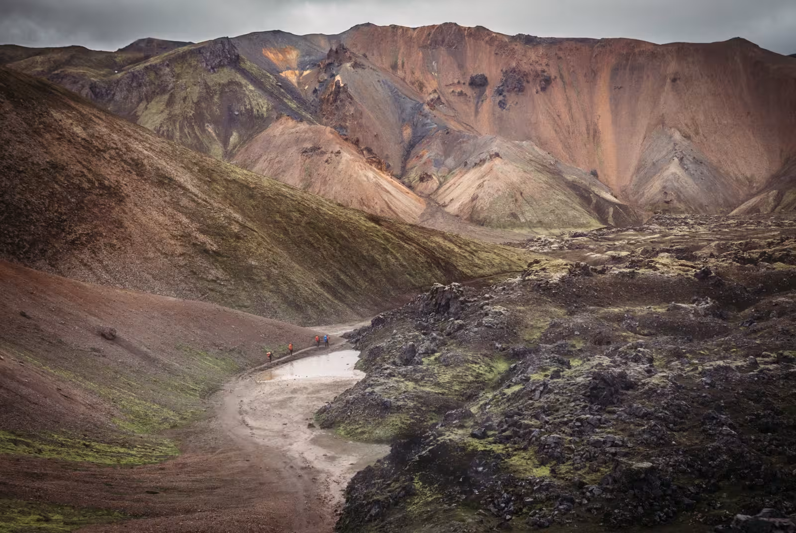 Hikers crossing a shallow river in the colorful volcanic mountains of Landmannalaugar, Iceland