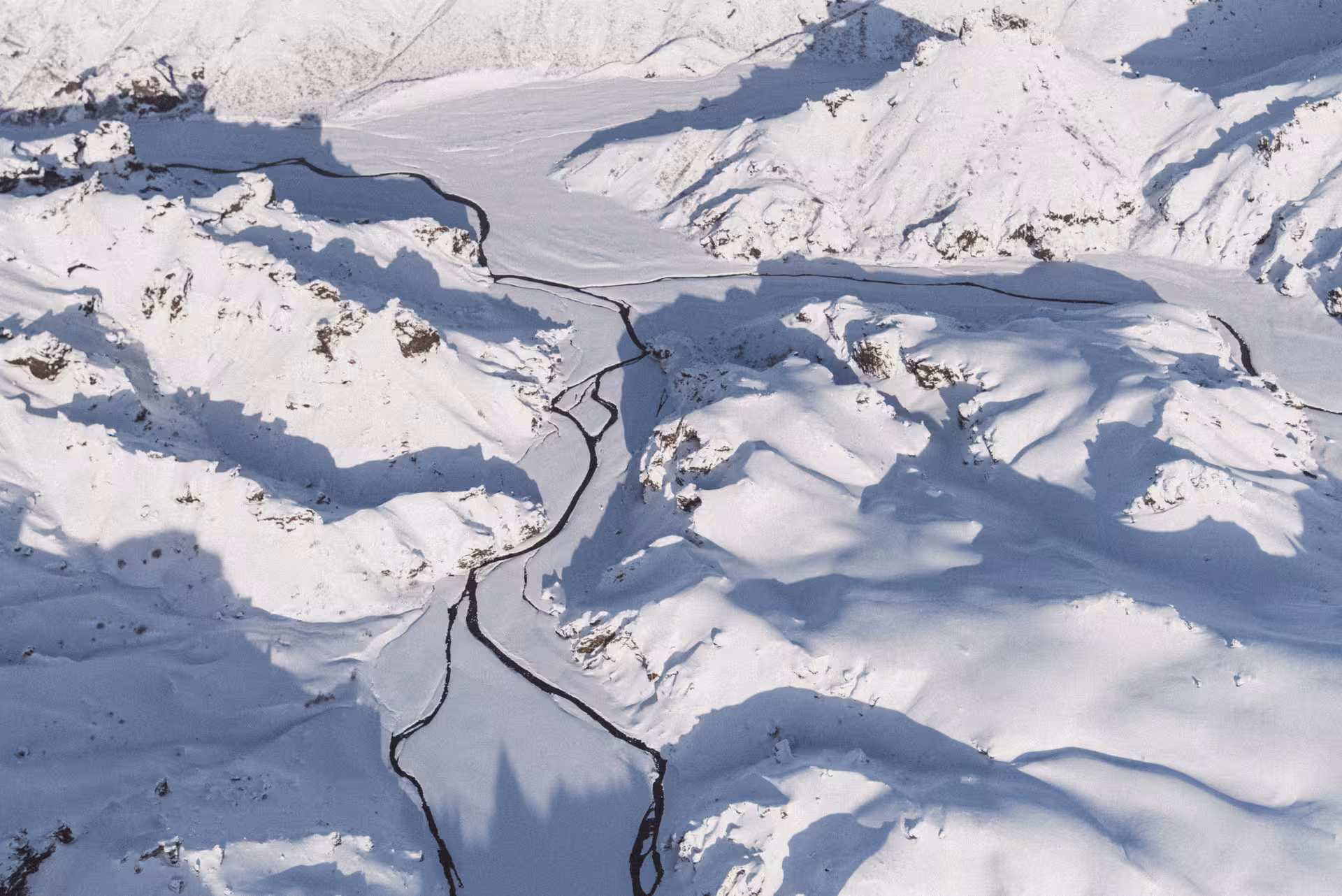 Aerial view of snow-covered mountains with a winding frozen river in Landmannalaugar, Iceland