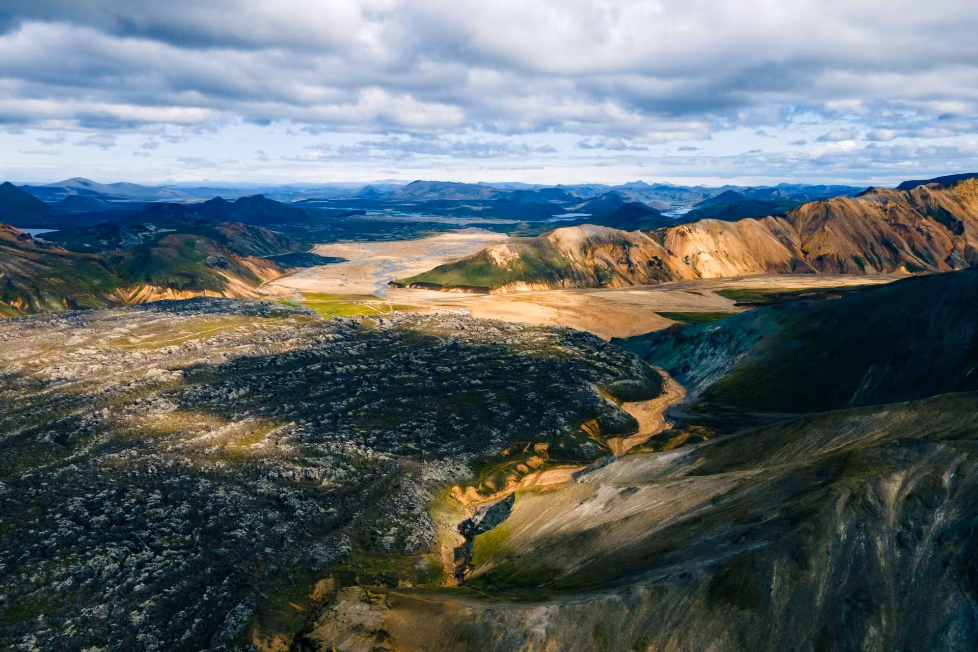 Aerial view of Landmannalaugar highlands with colorful rhyolite mountains, lava fields, and river valley in Iceland