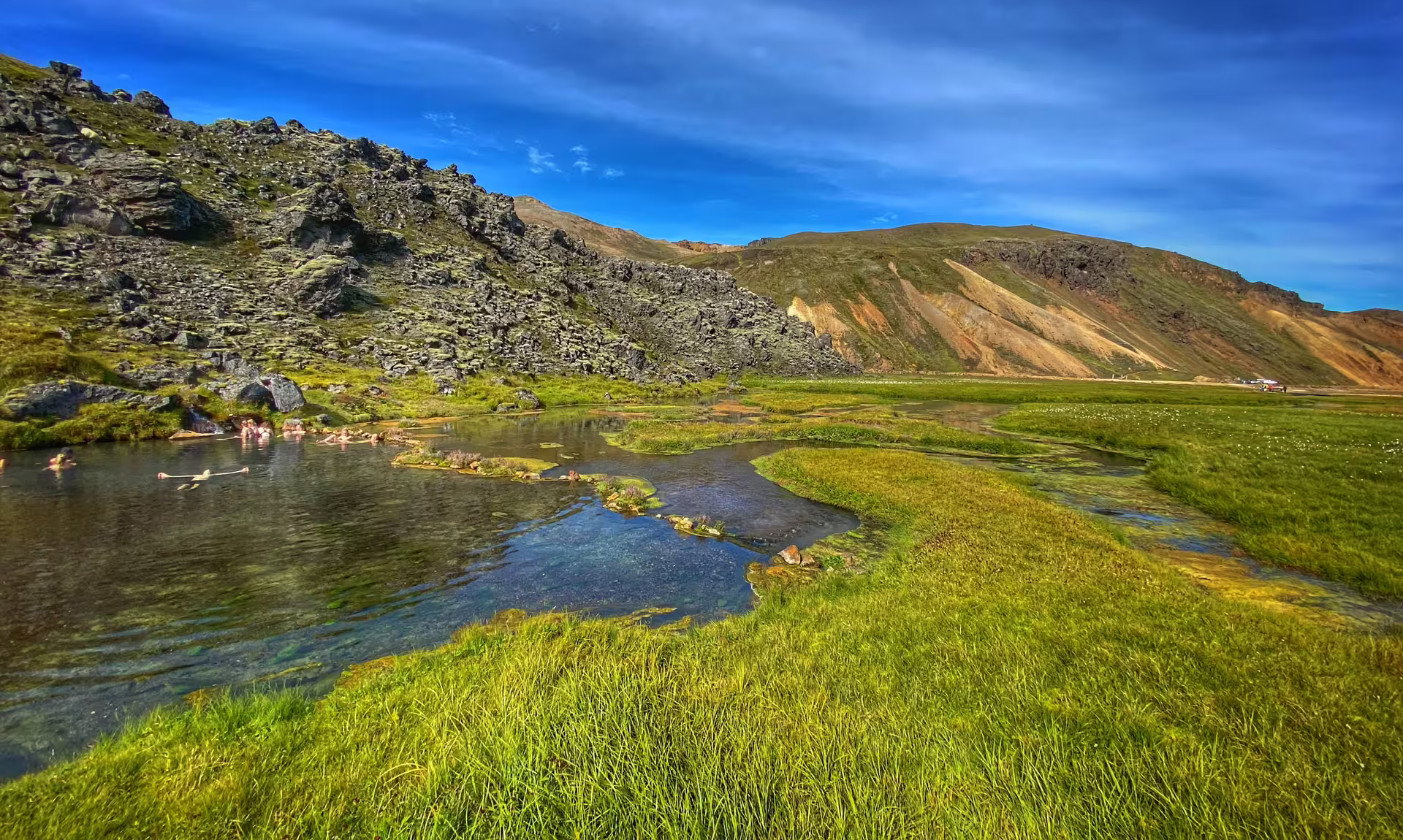 Geothermal hot spring river at Landmannalaugar highlands Iceland with colorful rhyolite mountains and green meadows