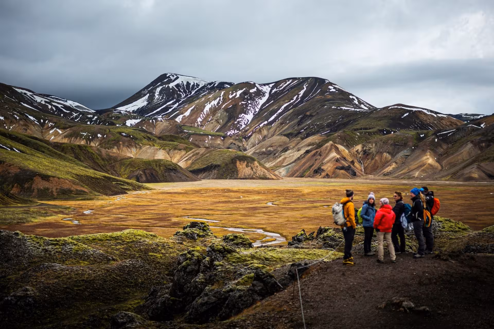 Group of hikers overlooking colorful rhyolite mountains and valley at Landmannalaugar Iceland Highlands
