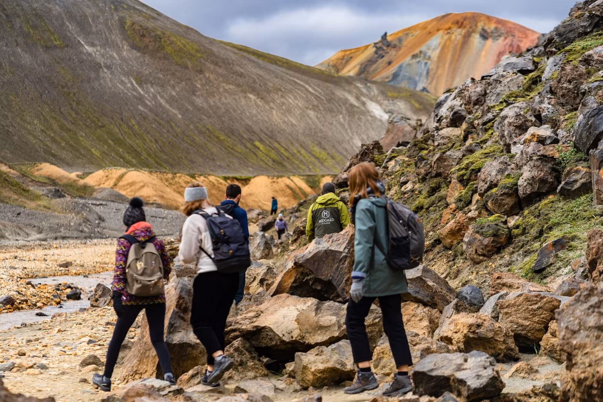 Hikers with backpacks exploring colorful rhyolite mountains at Landmannalaugar Iceland Highlands