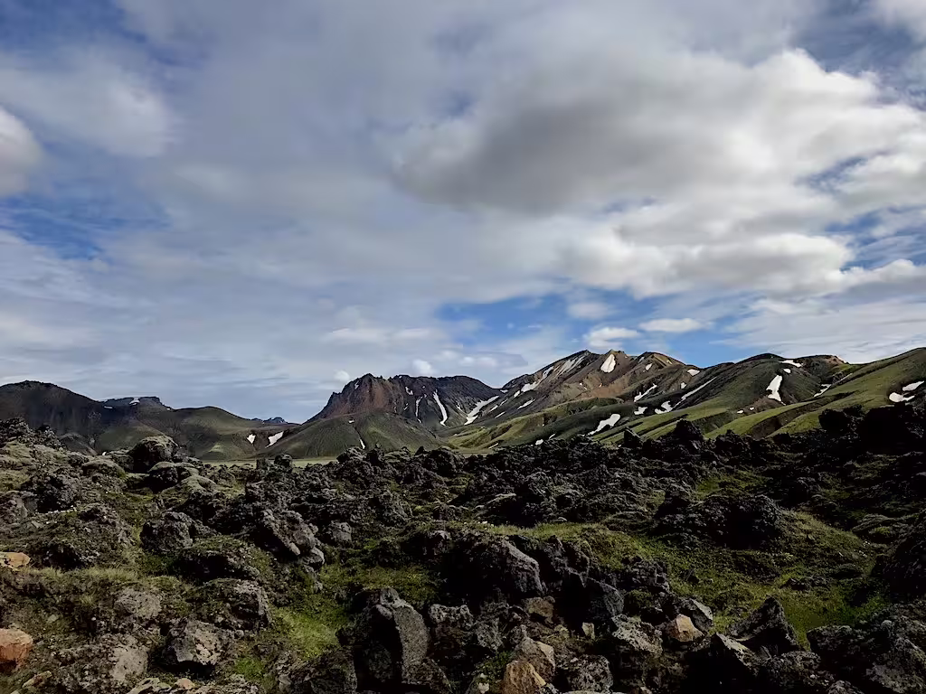 Volcanic lava fields with green mountains and snow patches at Landmannalaugar Highlands Iceland