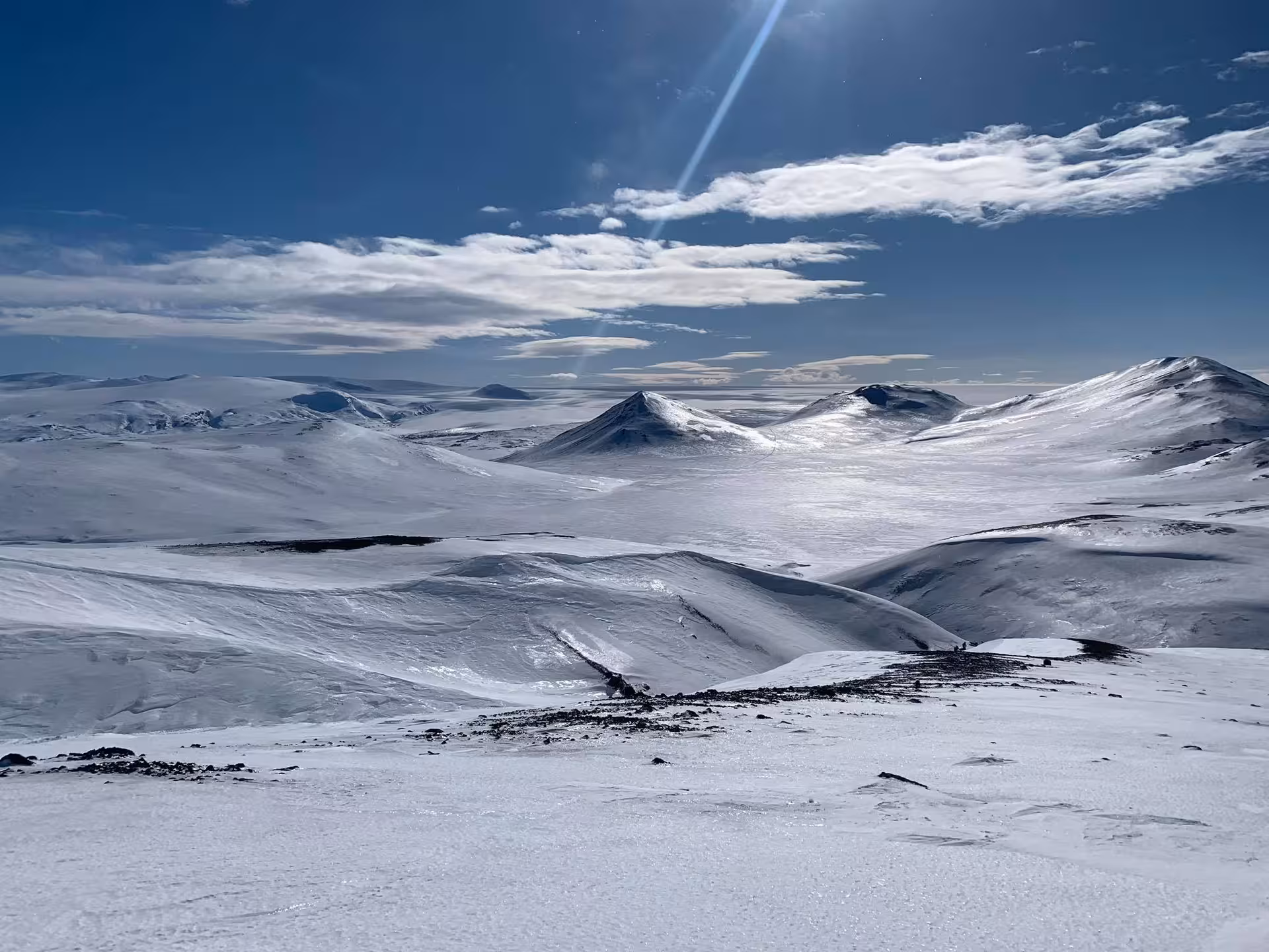 Snow-covered highland mountains under blue sky during snowmobiling tour in Landmannalaugar, Iceland