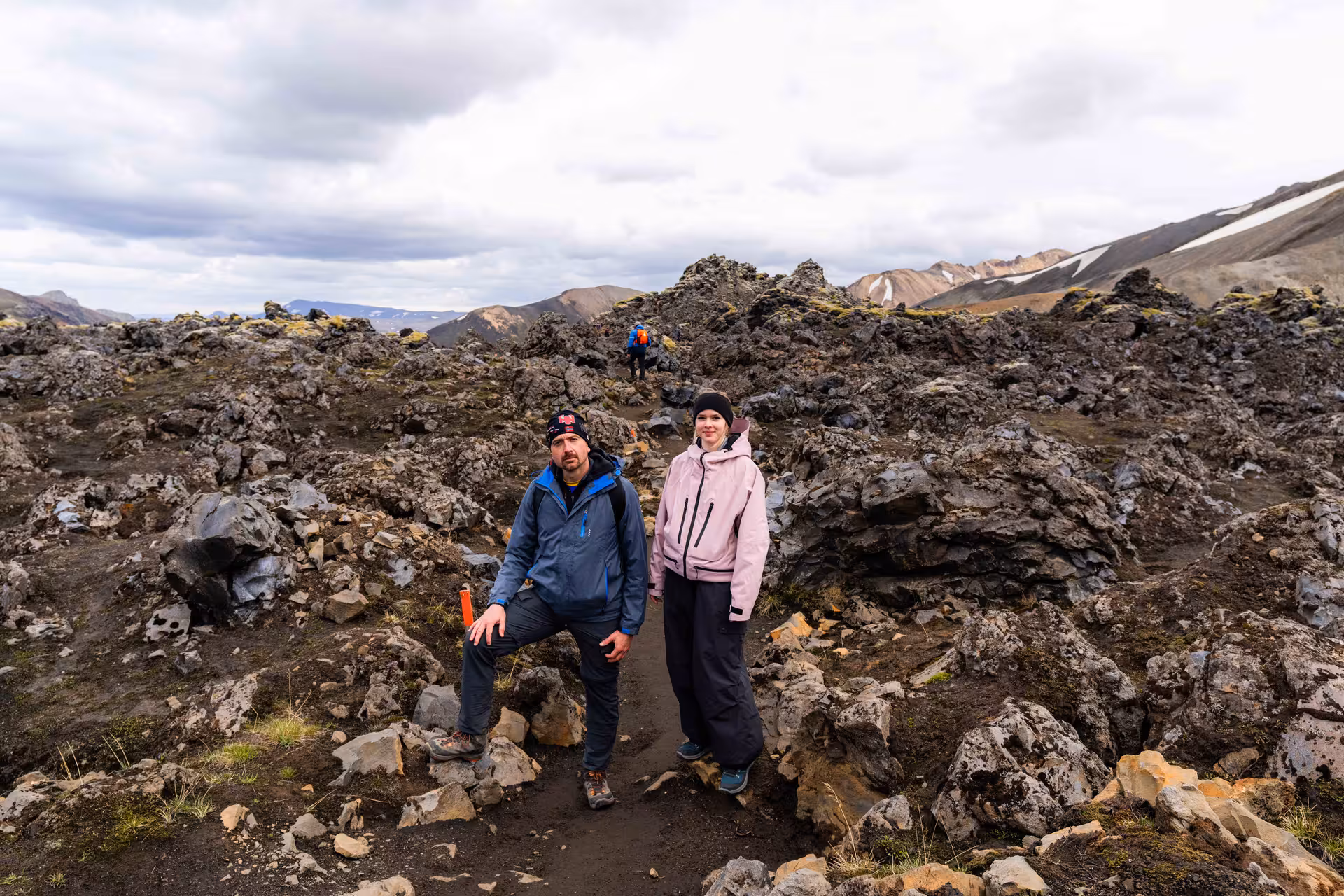 Two hikers standing on a rocky lava field trail at Landmannalaugar Highlands, Iceland